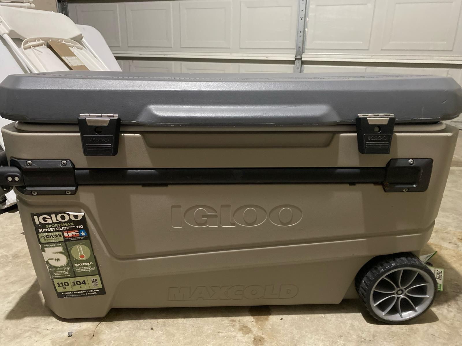 Tan Igloo cooler with black accents, wheels, and a gray lid.