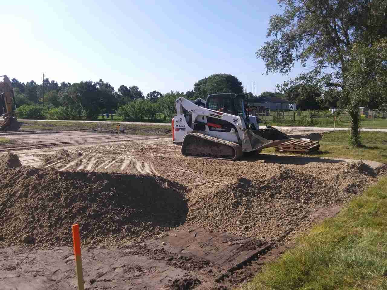 A Bobcat skid-steer loader on a gravel pile in an outdoor construction site.