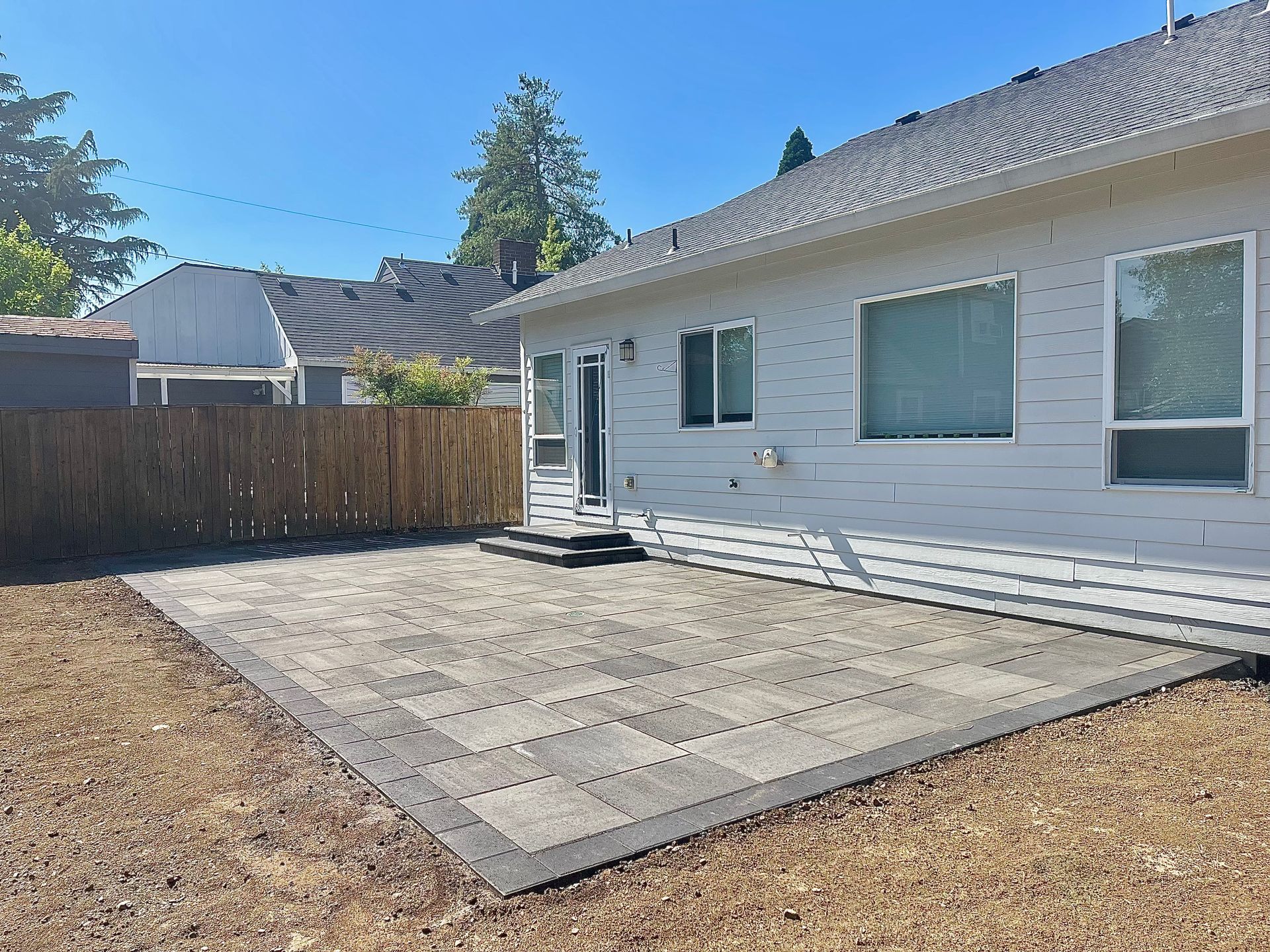 A white house with a fence and a patio in front of it.