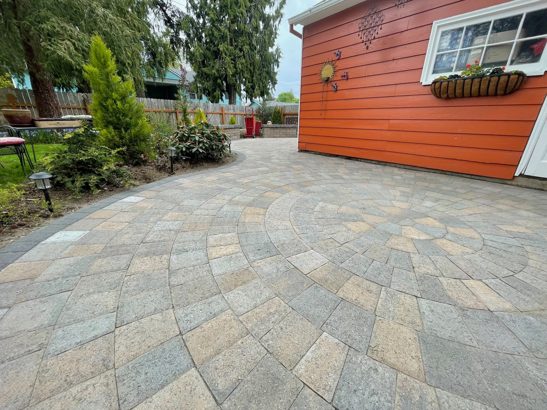 There is a patio in front of a red house.