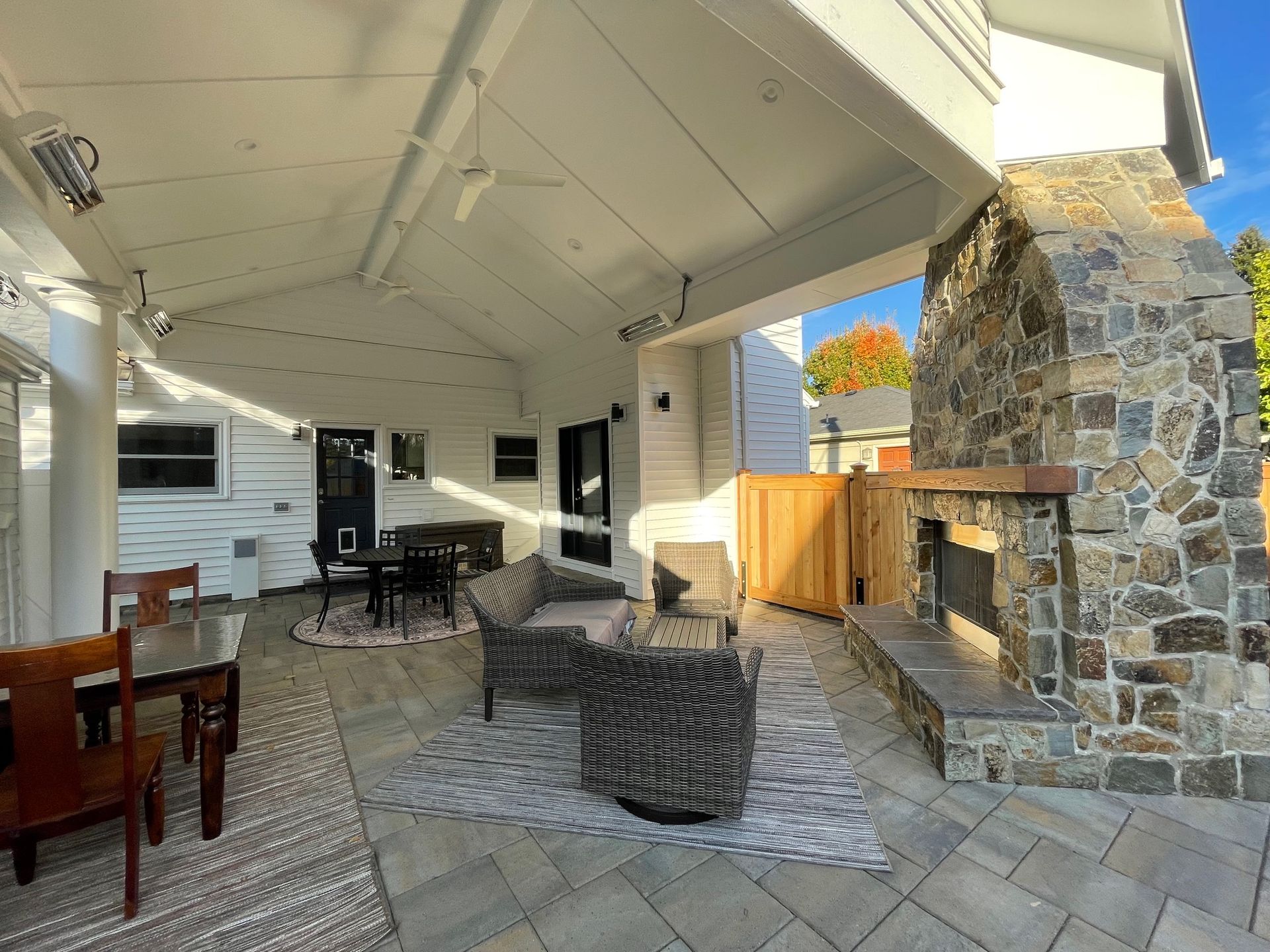 A patio with a stone fireplace and houses in the background