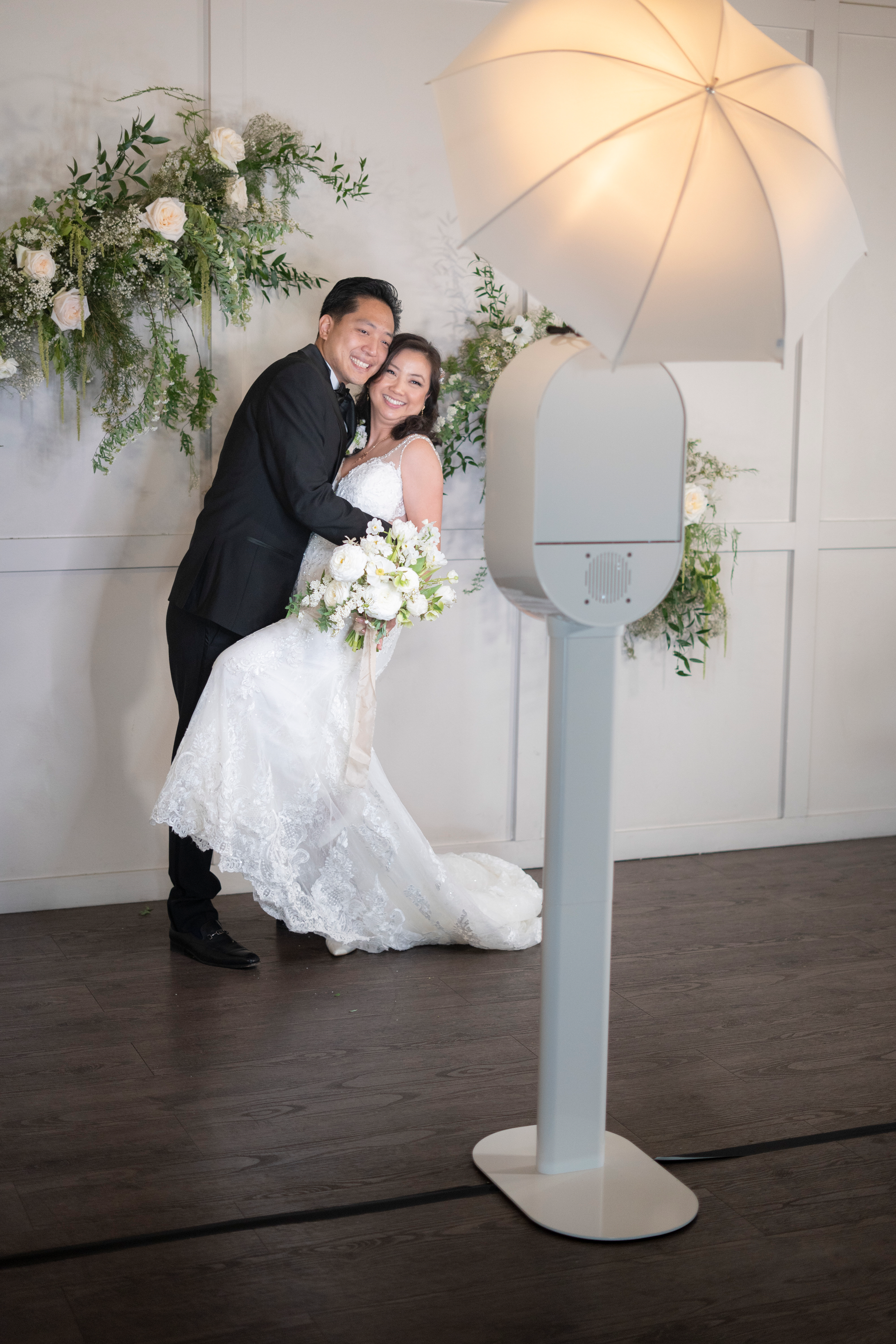A bride and groom are posing for a picture in front of a photo booth.