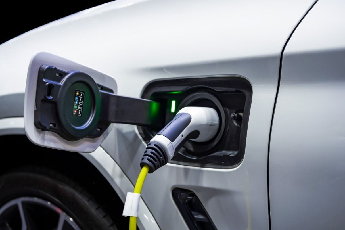 Electric car charging at a plug-in port on a silver vehicle