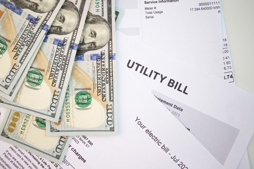 Dollar bills beside a utility bill statement on a white background