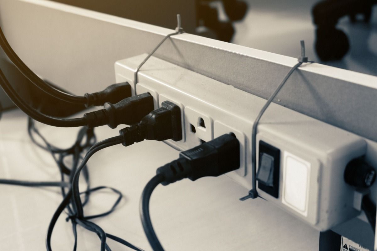 Power strip with multiple plugs and cables connected behind a desk