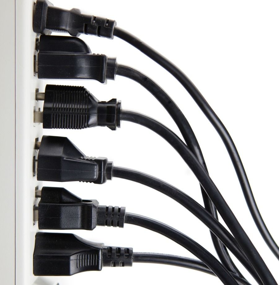 Black power cords plugged into a white power strip, viewed from the side.