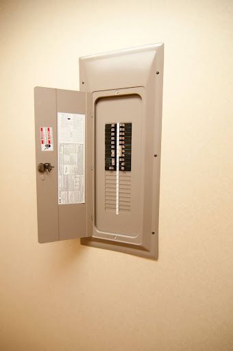 Open electrical breaker panel mounted on a beige wall.