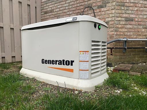 White outdoor generator beside a brick wall, with green indicator lights and vented side panel.