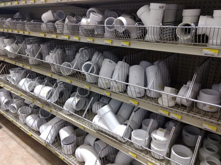 A store shelf filled with lots of white pipes and fittings