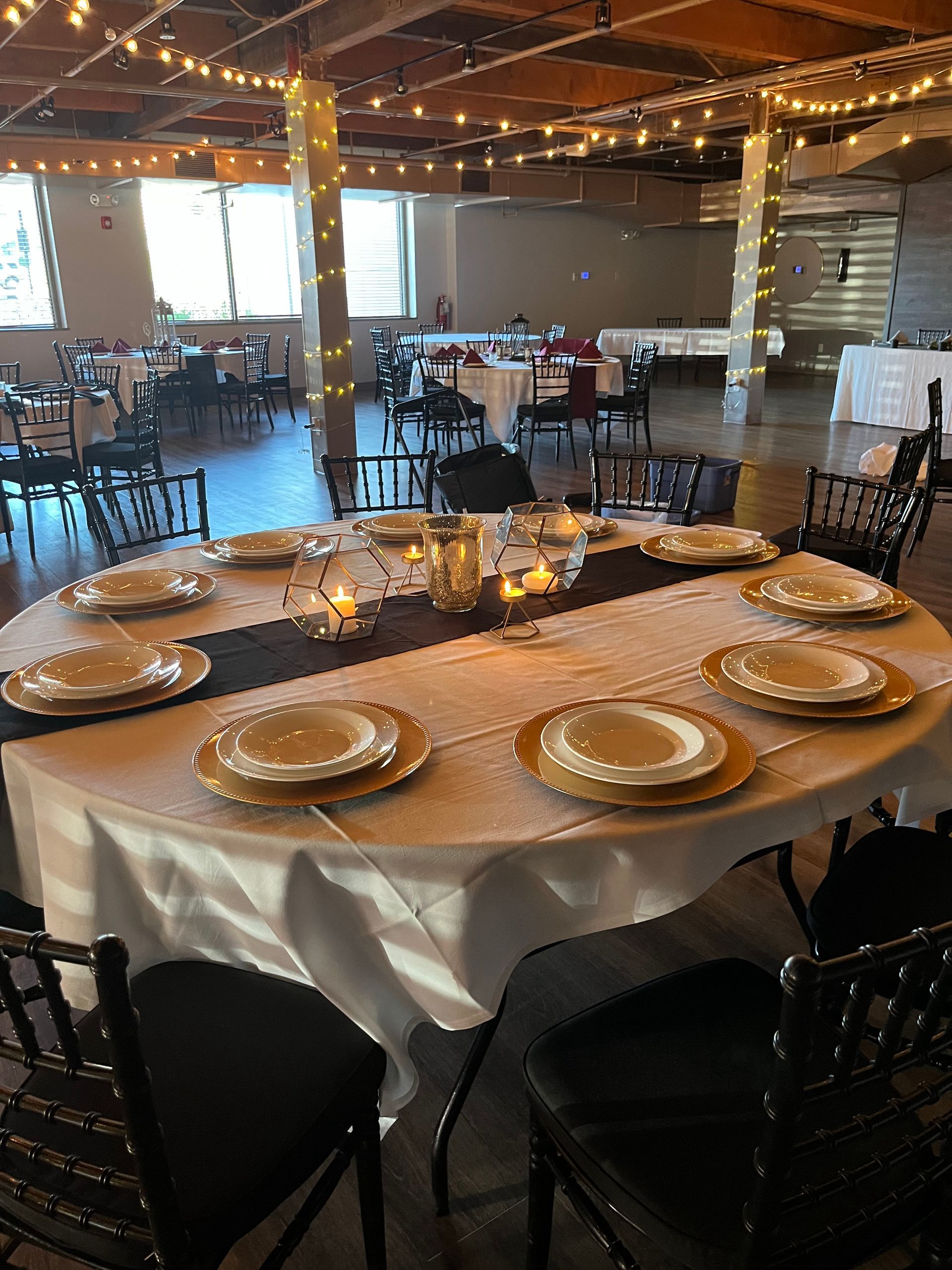 Round banquet table set with plates and candles in a warmly lit event hall