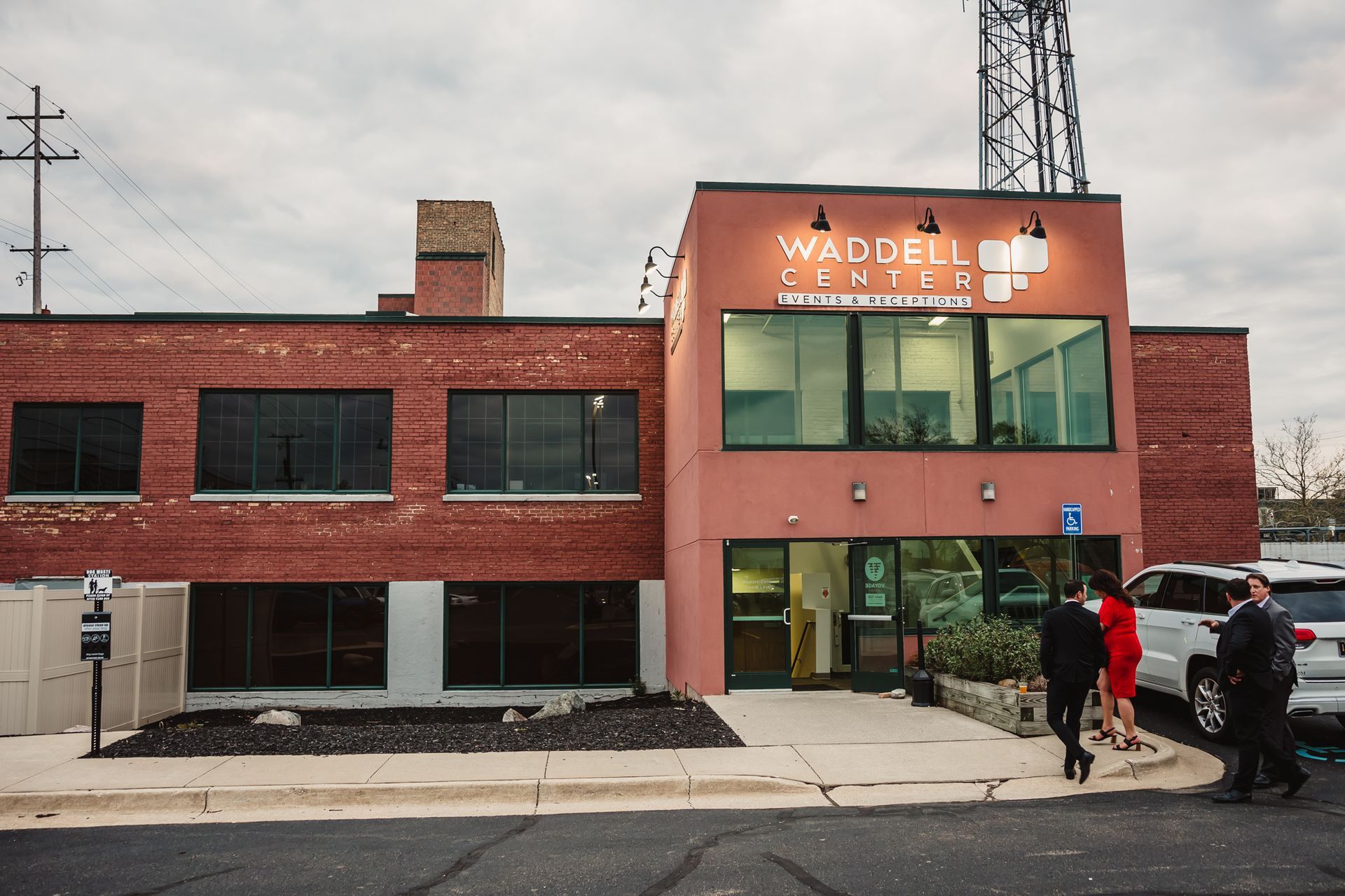 Brick storefront with large windows and “Waddle” sign; two people stand outside on the sidewalk.