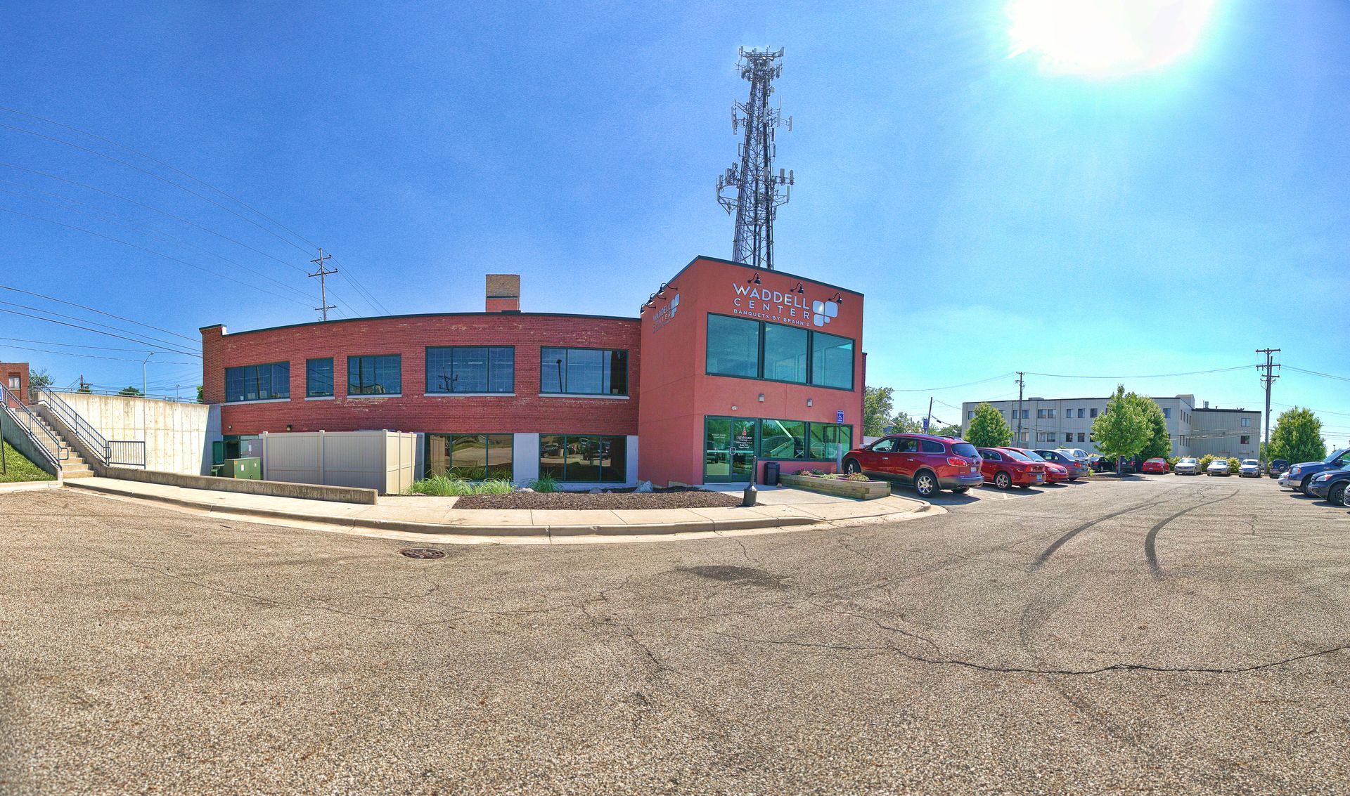 Red brick office building with parking lot and communication tower on a sunny day