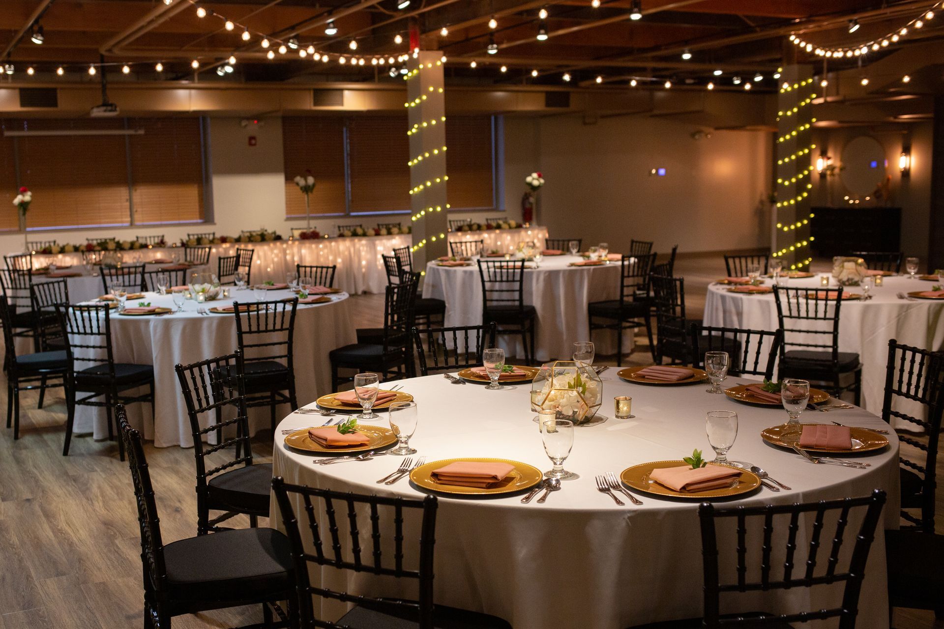 Banquet hall with round tables set for a formal event under warm string lights