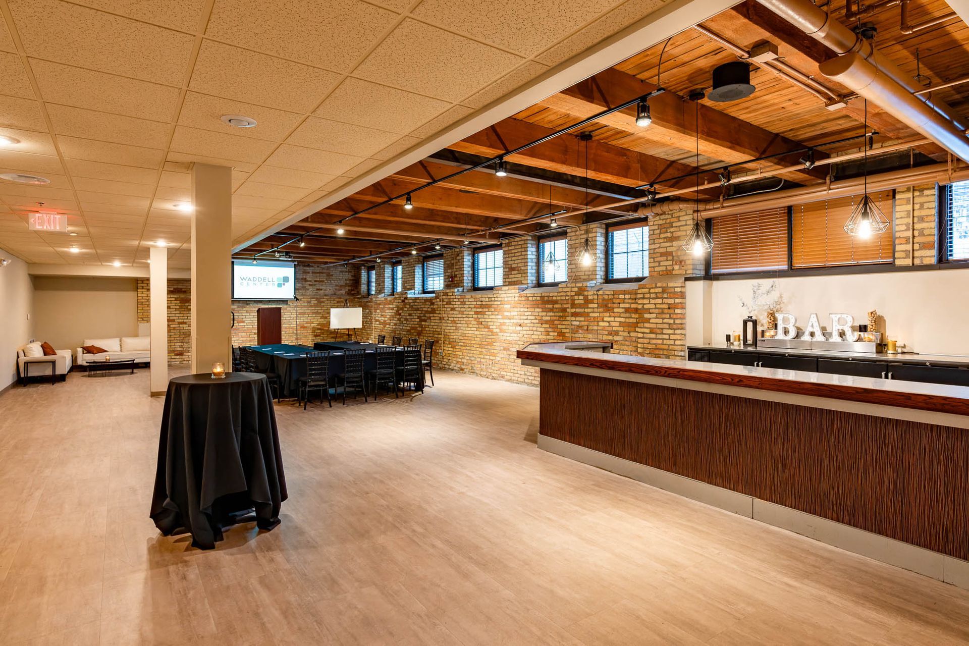 Spacious basement lounge with exposed wood ceiling, bar counter, and seating area.