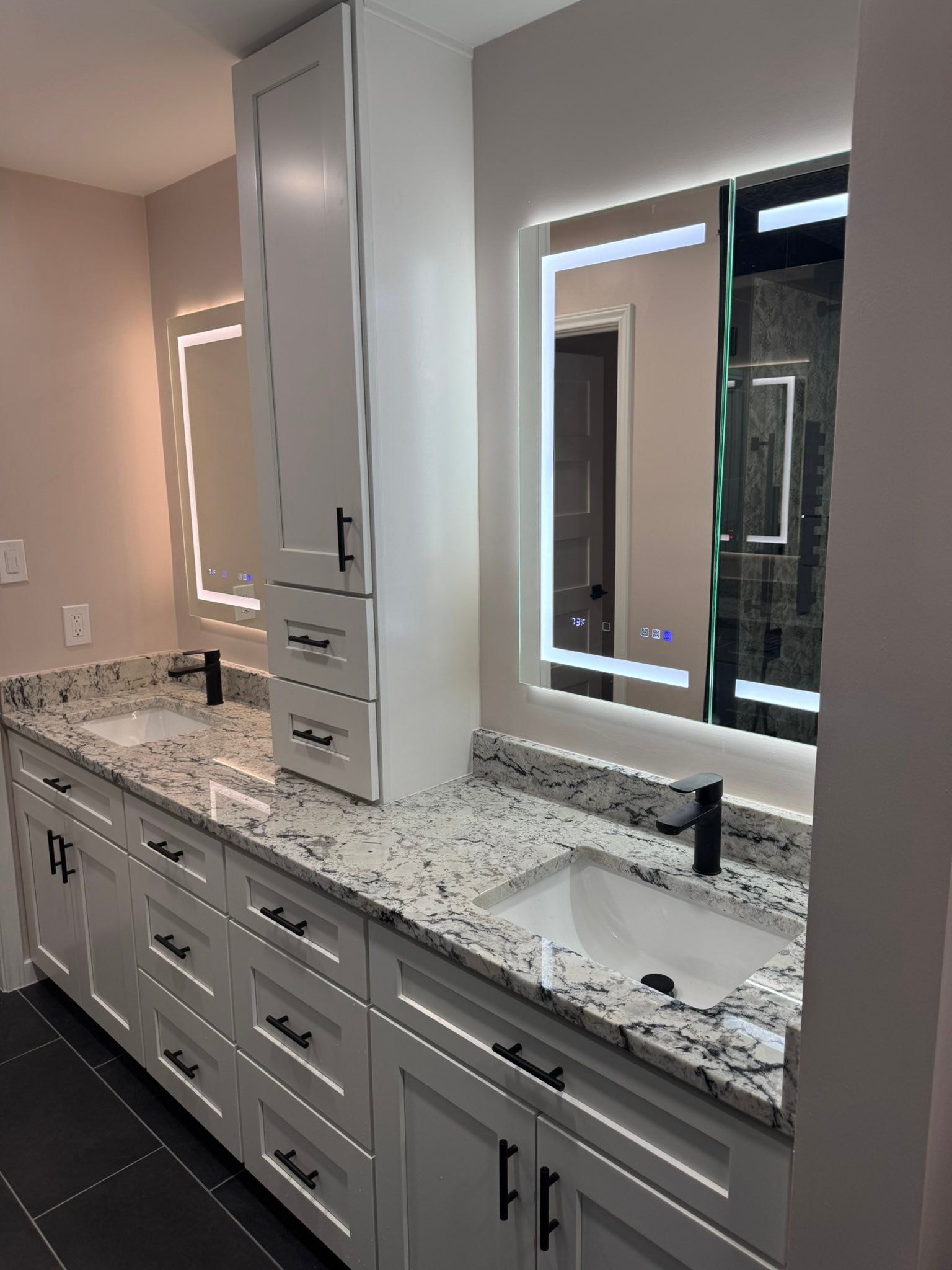 Modern bathroom vanity with double sinks, gray cabinets, speckled countertop, and large mirrors.