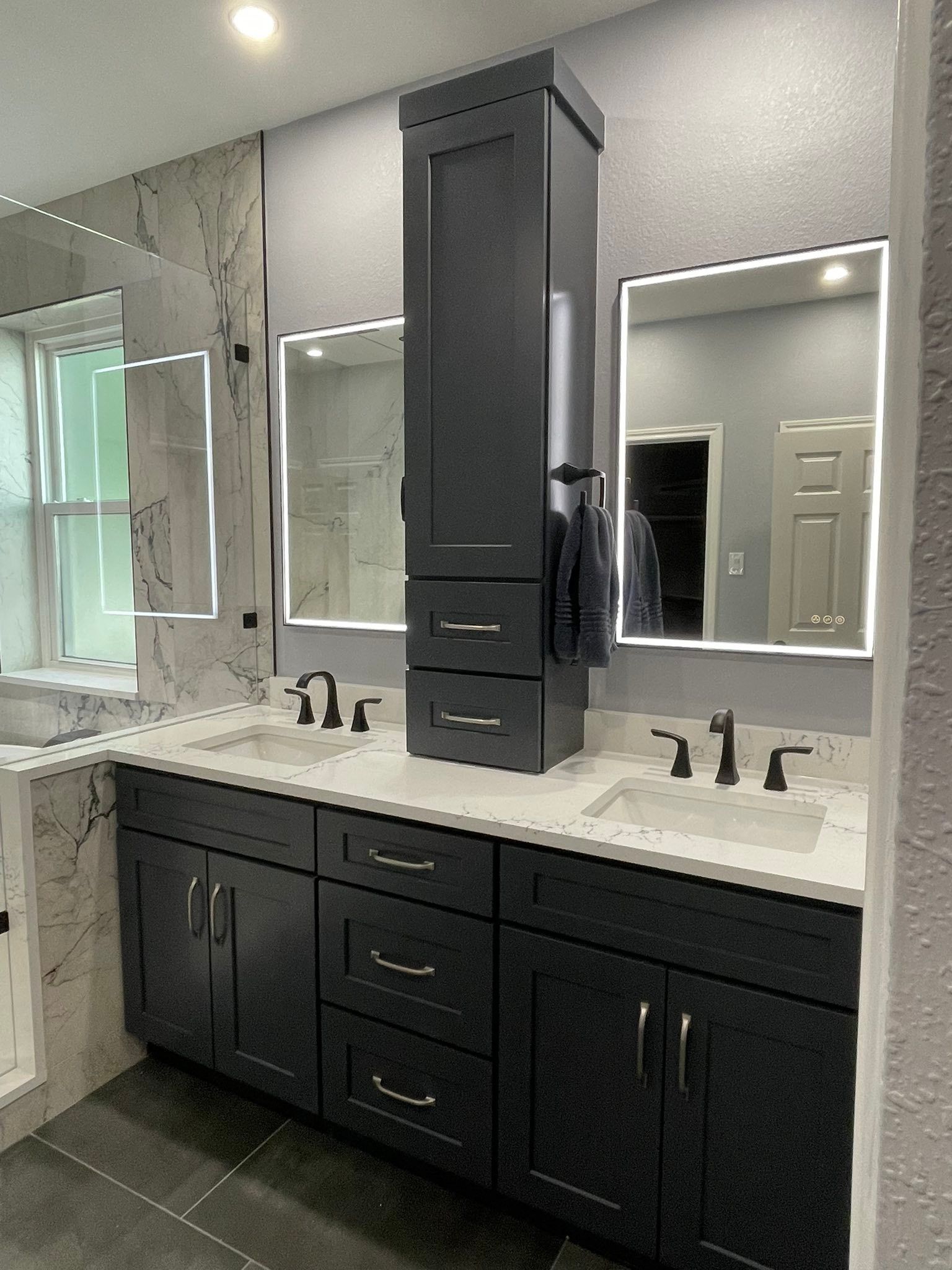 Modern bathroom vanity with double sinks, black cabinetry, mirrors, and built-in lighting