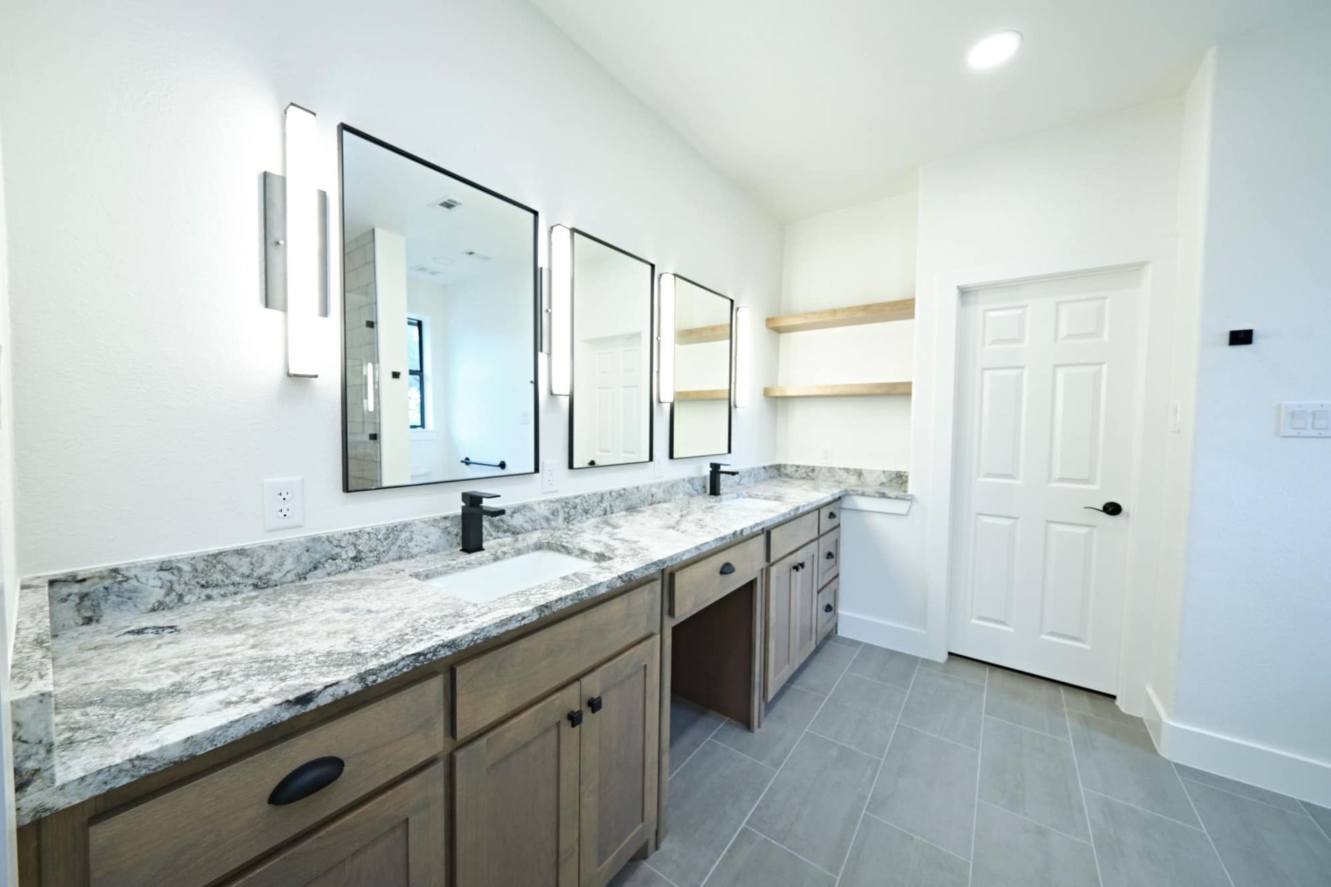 Bright modern bathroom vanity with marble countertop, three mirrors, and white door.