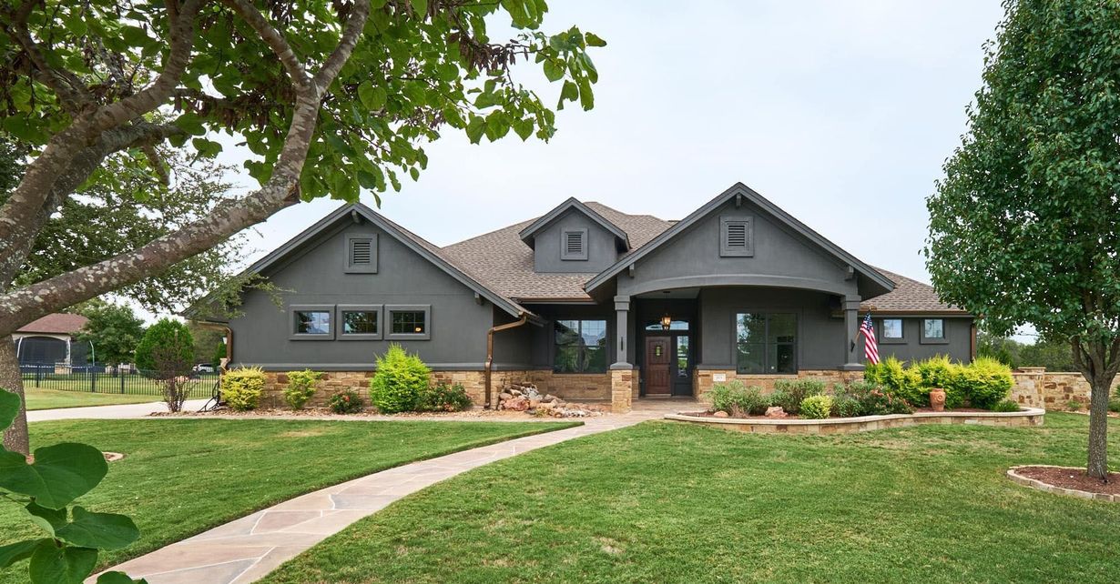 Single-story gray house with a landscaped front yard and stone walkway.