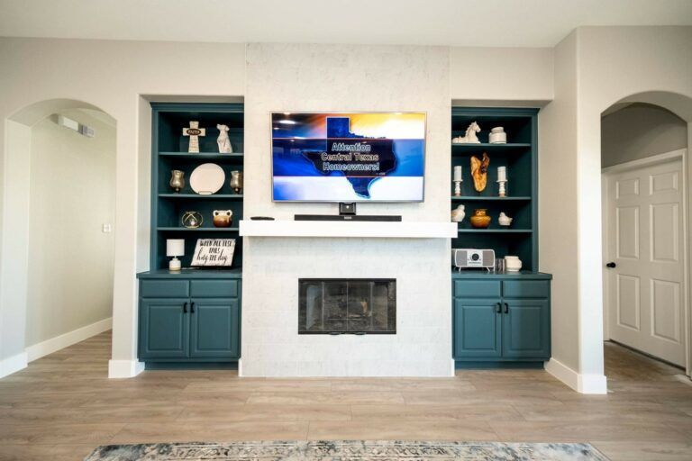 Living room wall with mounted TV, fireplace, and teal built-in shelves and cabinets