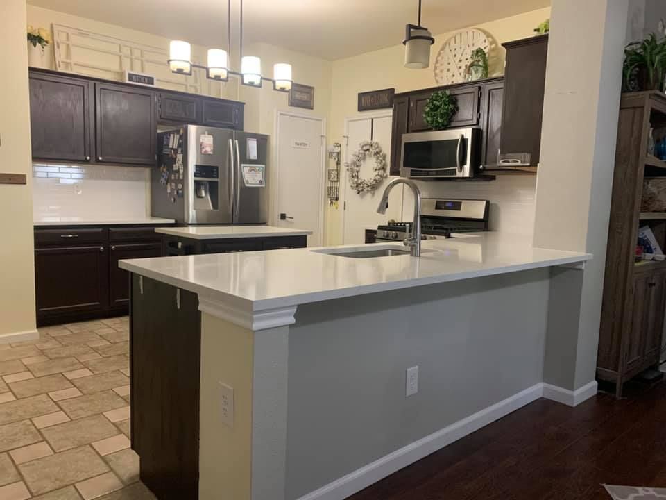 Modern kitchen with dark cabinets, stainless appliances, and a white island countertop