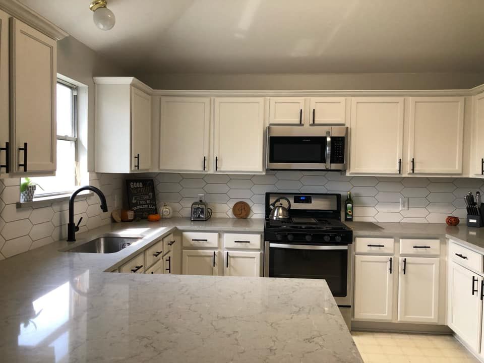 Bright kitchen with white cabinets, stainless steel appliances, and a large marble island.