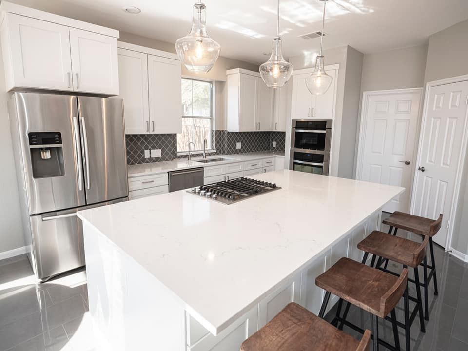 Bright modern kitchen with white cabinets, stainless appliances, large island, and bar stools
