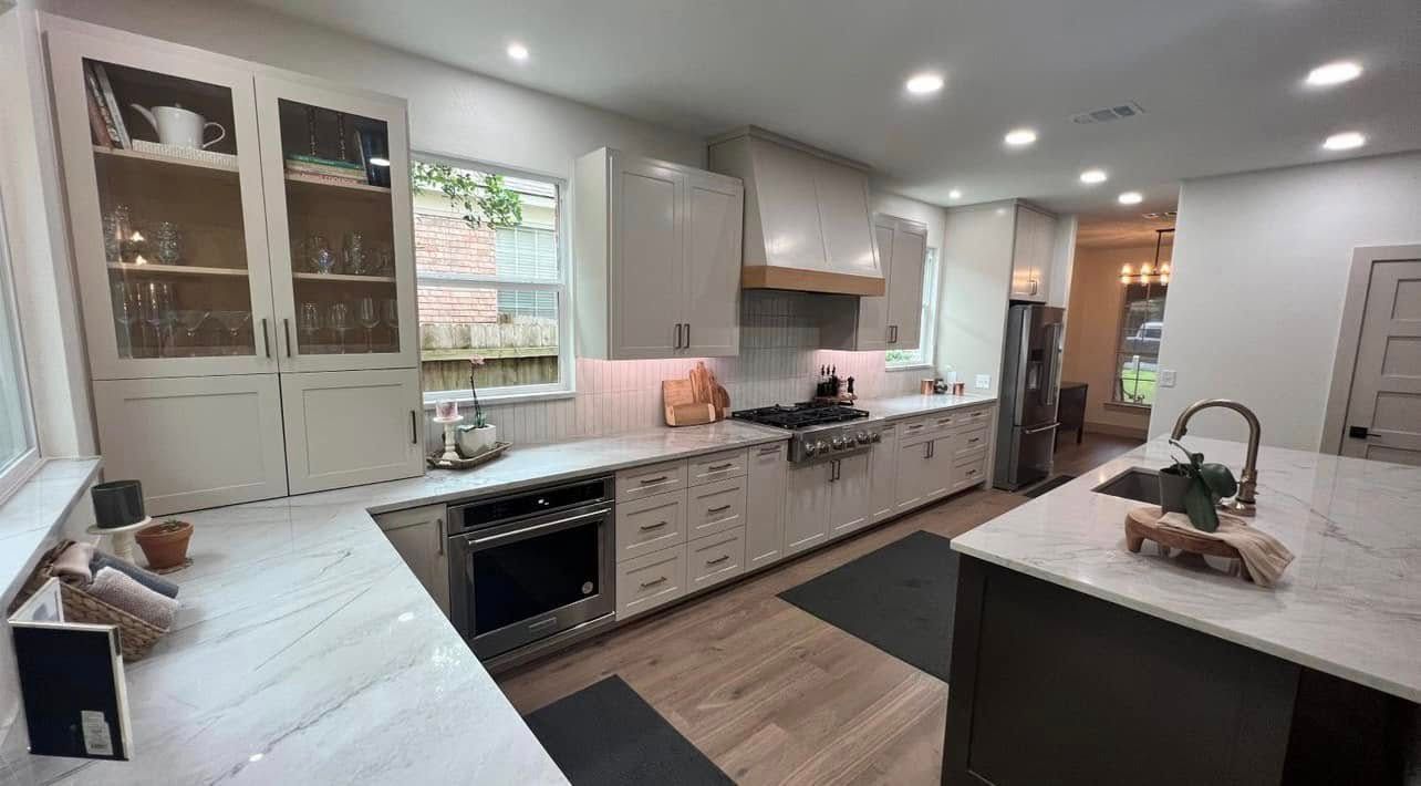 Bright modern kitchen with white cabinets, black countertops, island, and a window over the sink