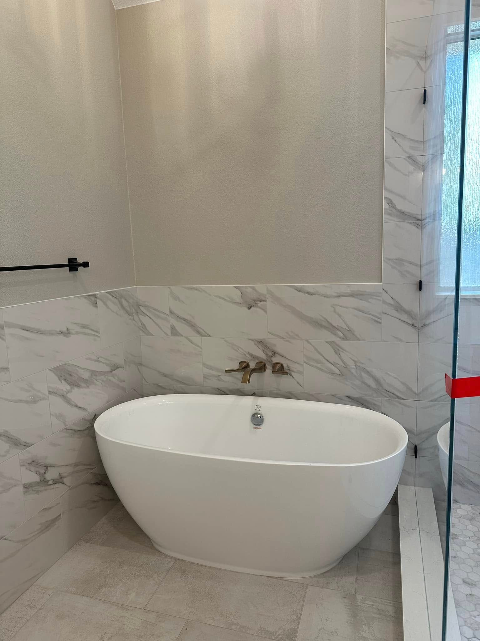 Modern bathroom with a white freestanding bathtub and marble-patterned walls.