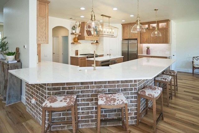 Modern kitchen with brick breakfast bar, white countertops, and three stools