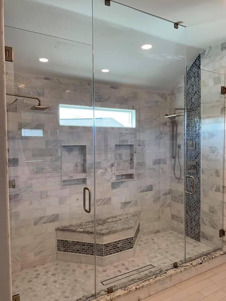 Glass-enclosed tiled shower with built-in bench, rain showerhead, and mosaic accent wall