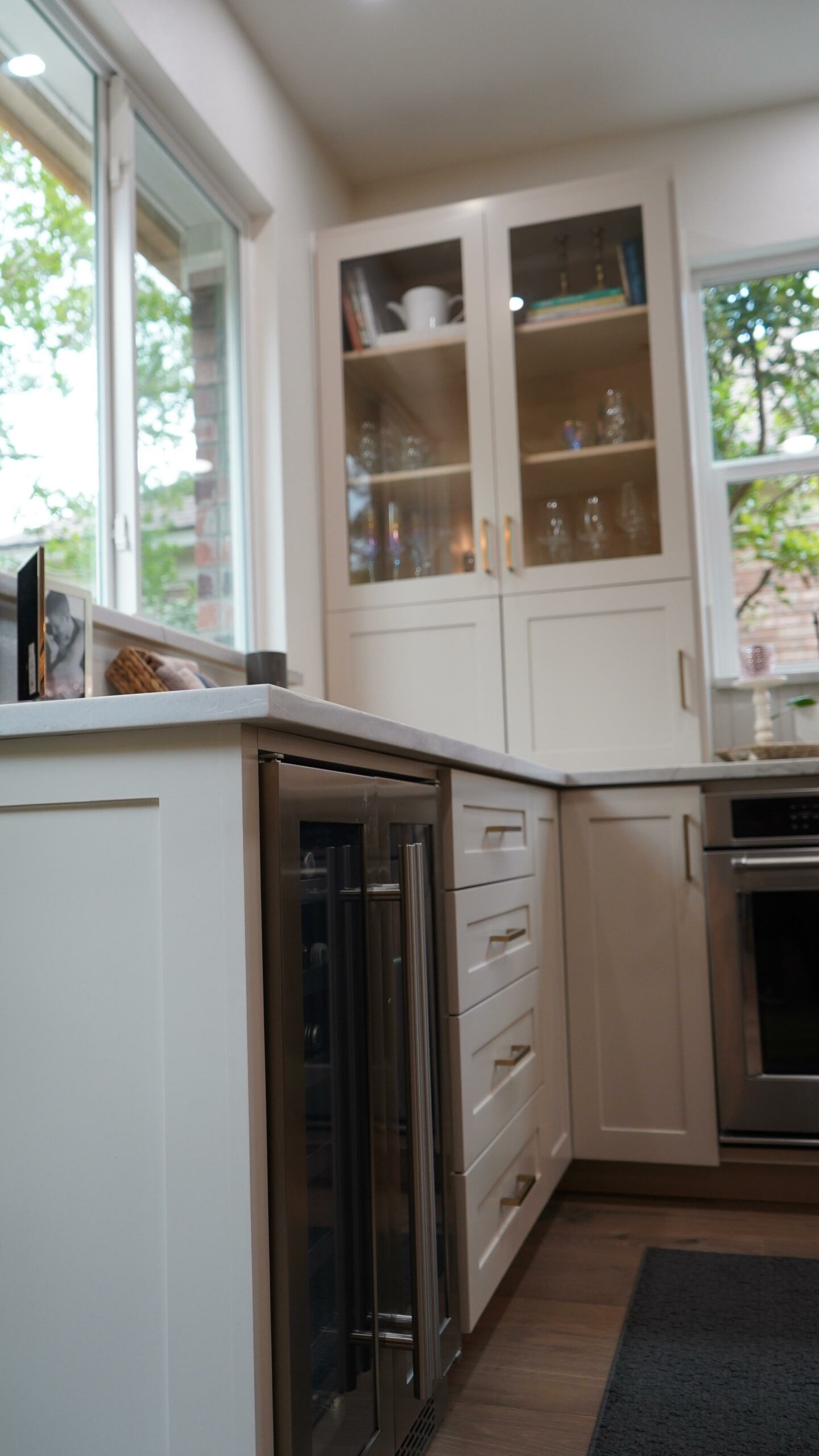 Bright kitchen with white cabinets, glass-front cupboards, and a window over the counter.