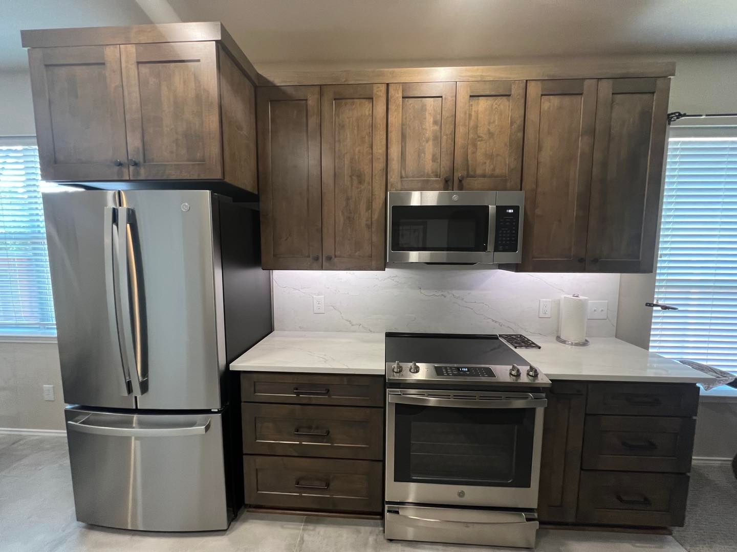 Compact kitchen with stainless appliances, dark wood cabinets, and light countertops