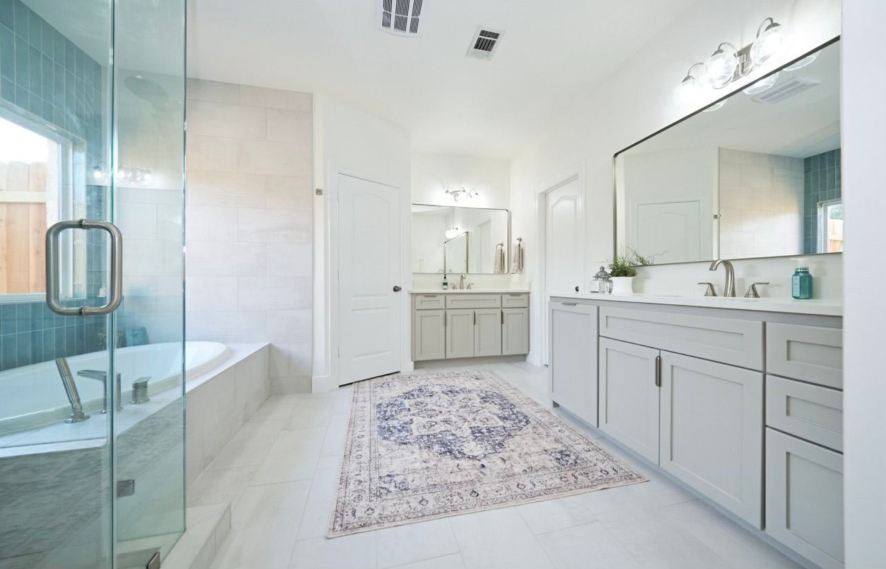 Bright modern bathroom with glass shower, soaking tub, double vanity, and large mirror