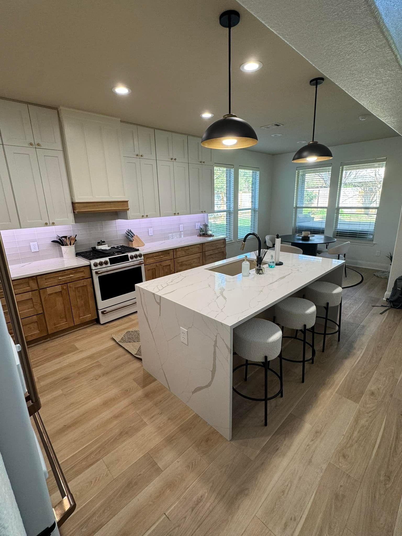Modern kitchen with white cabinets, large island, pendant lights, and wood flooring