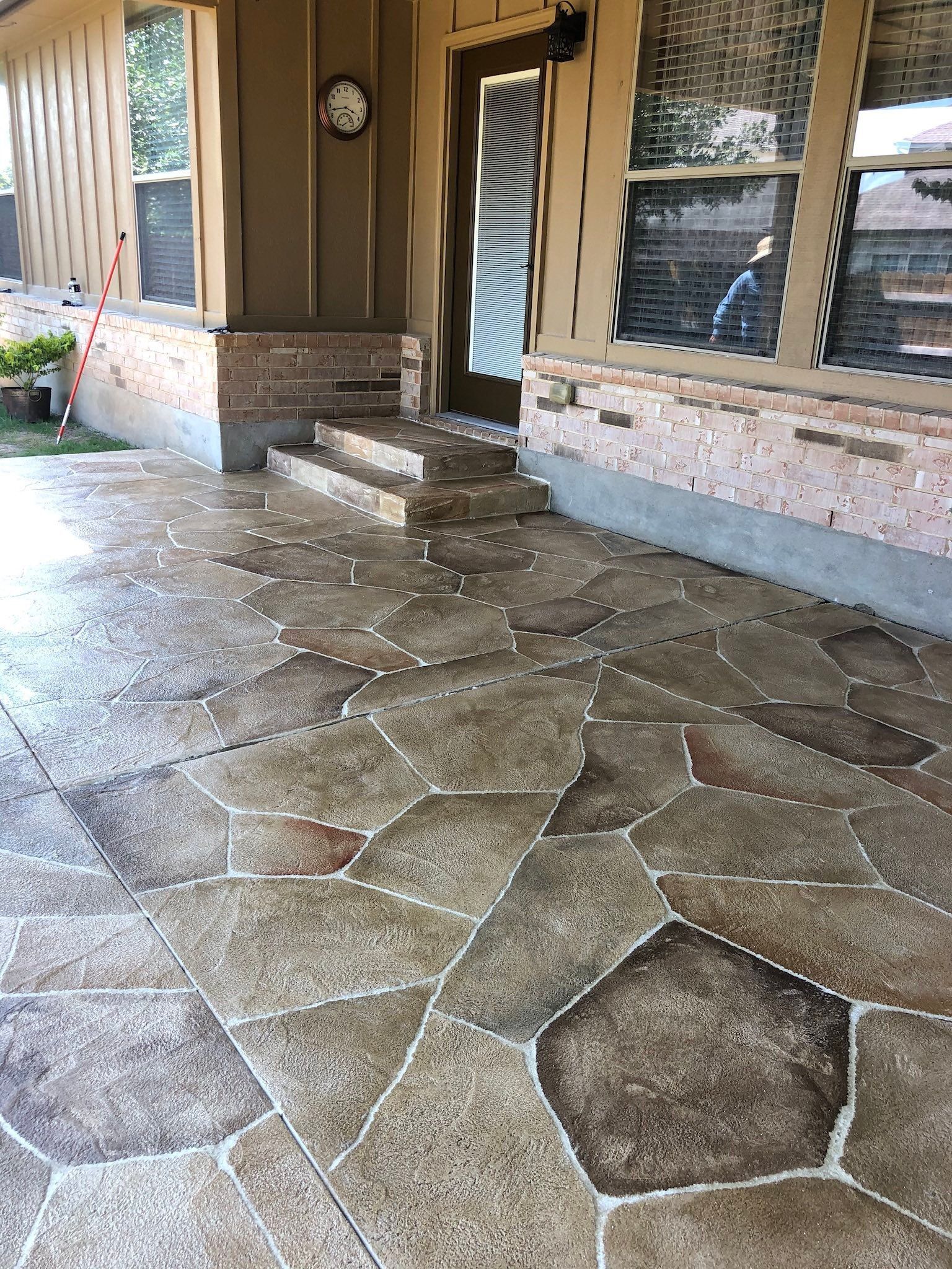 Stone front porch with steps, a door, and large windows in a house entryway