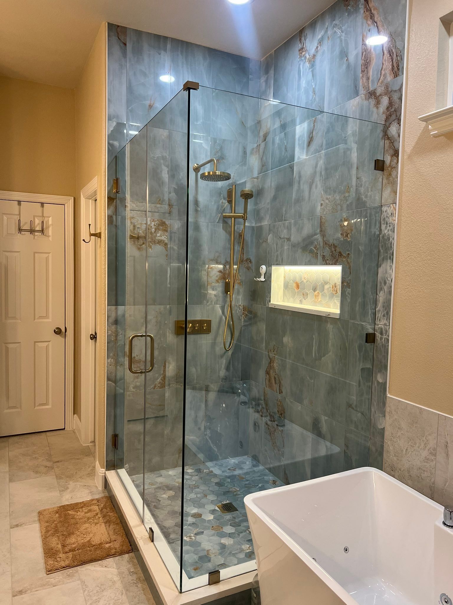 Luxury bathroom with glass-enclosed marble shower and a white soaking tub in the foreground