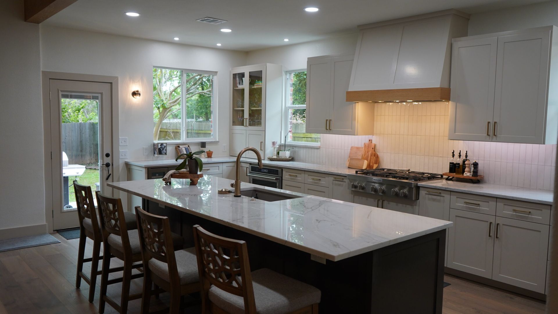 Bright modern kitchen with white cabinets, large island, pendant lights, and chairs by the counter