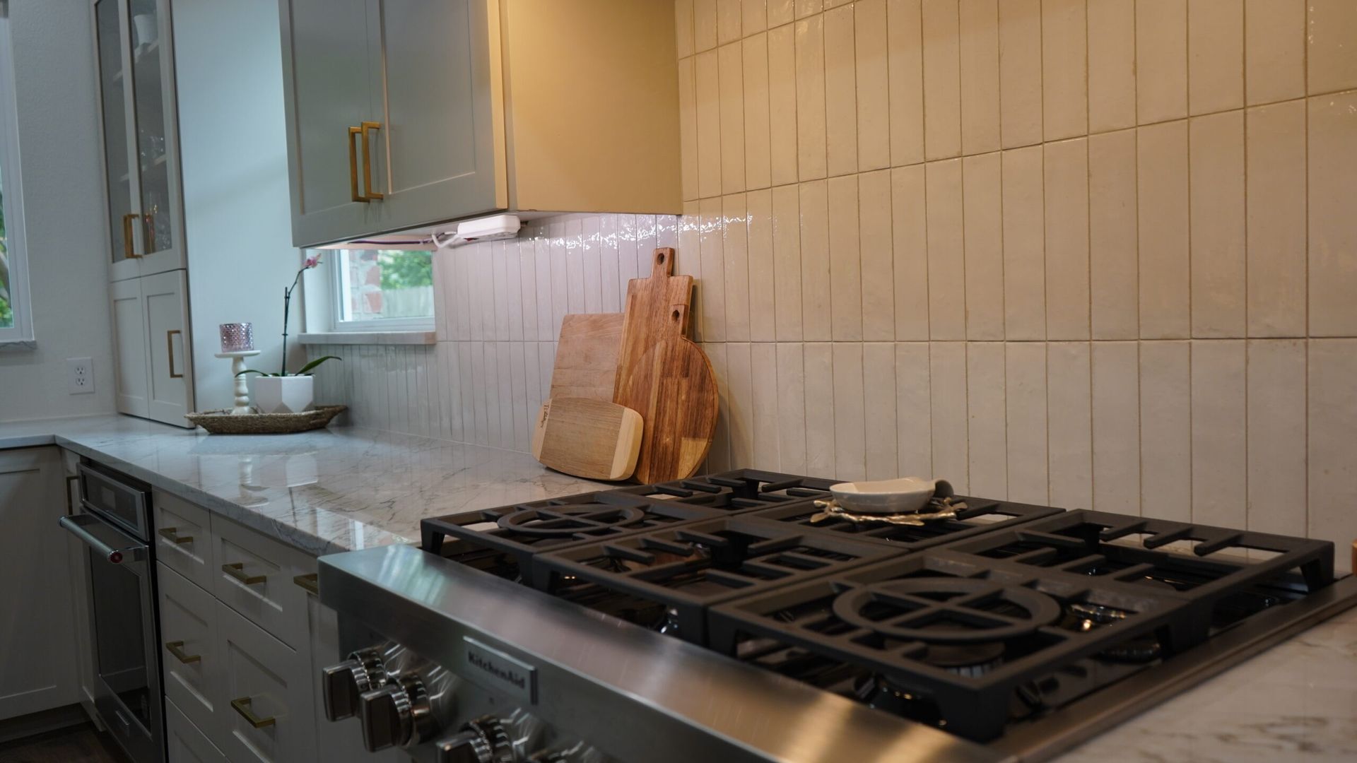 Modern kitchen with stainless stove, white tile backsplash, and wooden cutting boards on the counter
