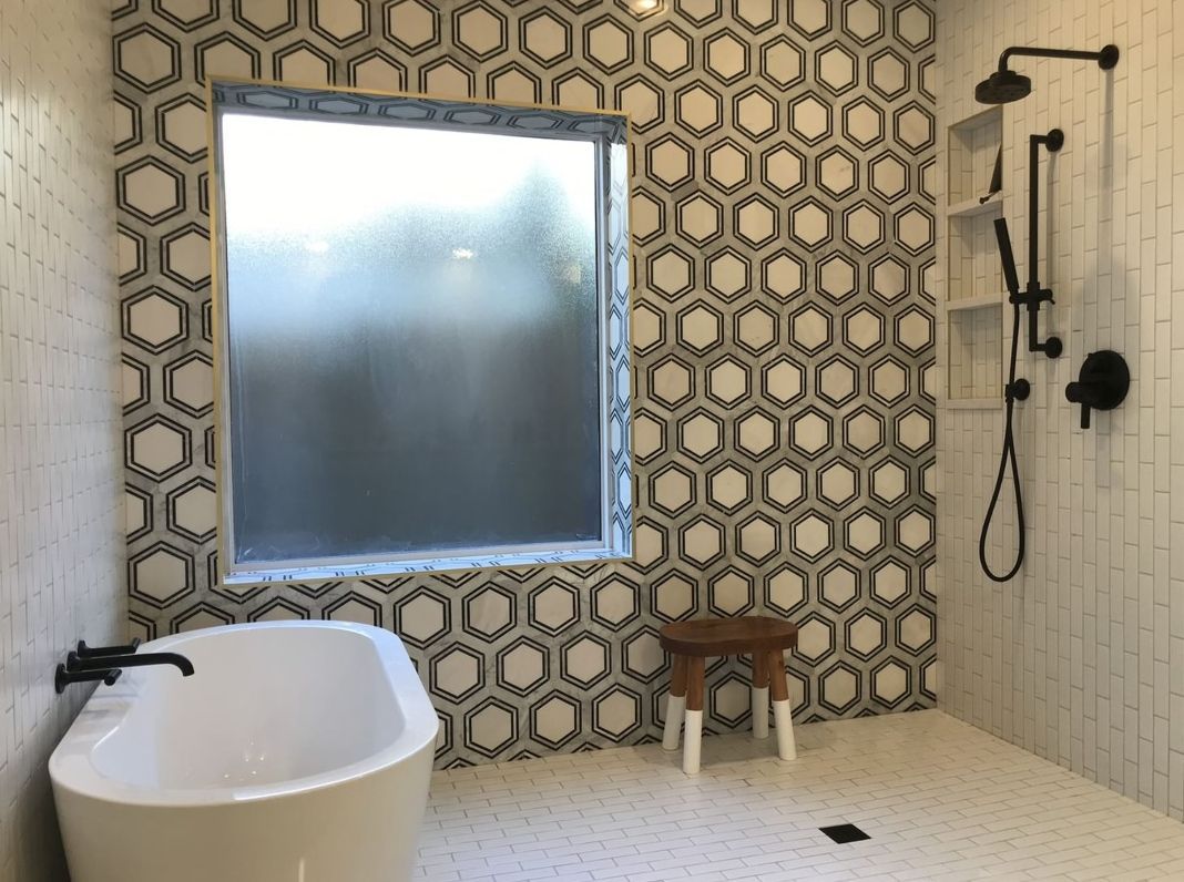 Modern bathroom with frosted window, hex tile shower wall, and white freestanding tub