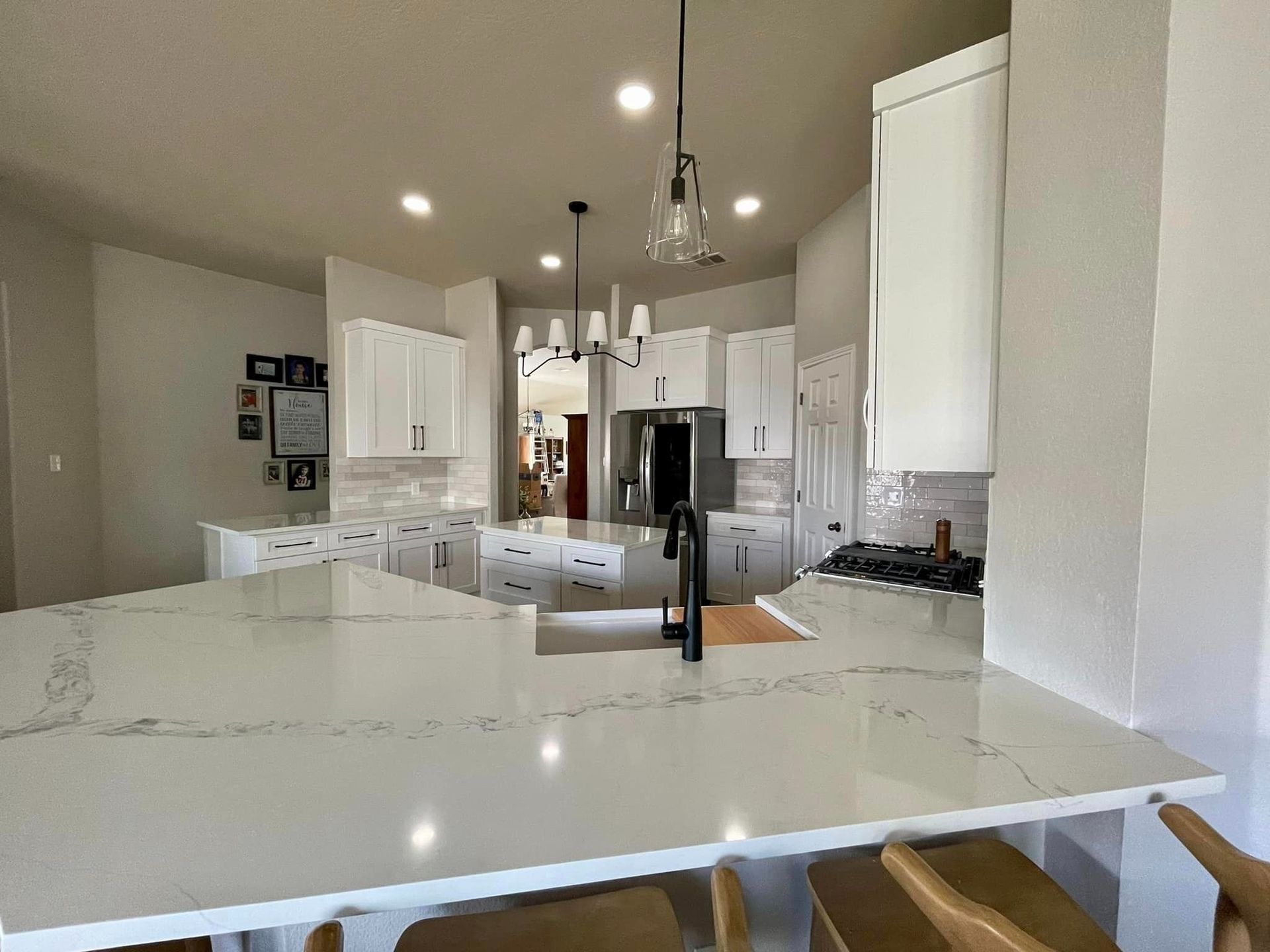 Bright modern kitchen with white cabinets, marble island, pendant lights, and stainless steel appliances