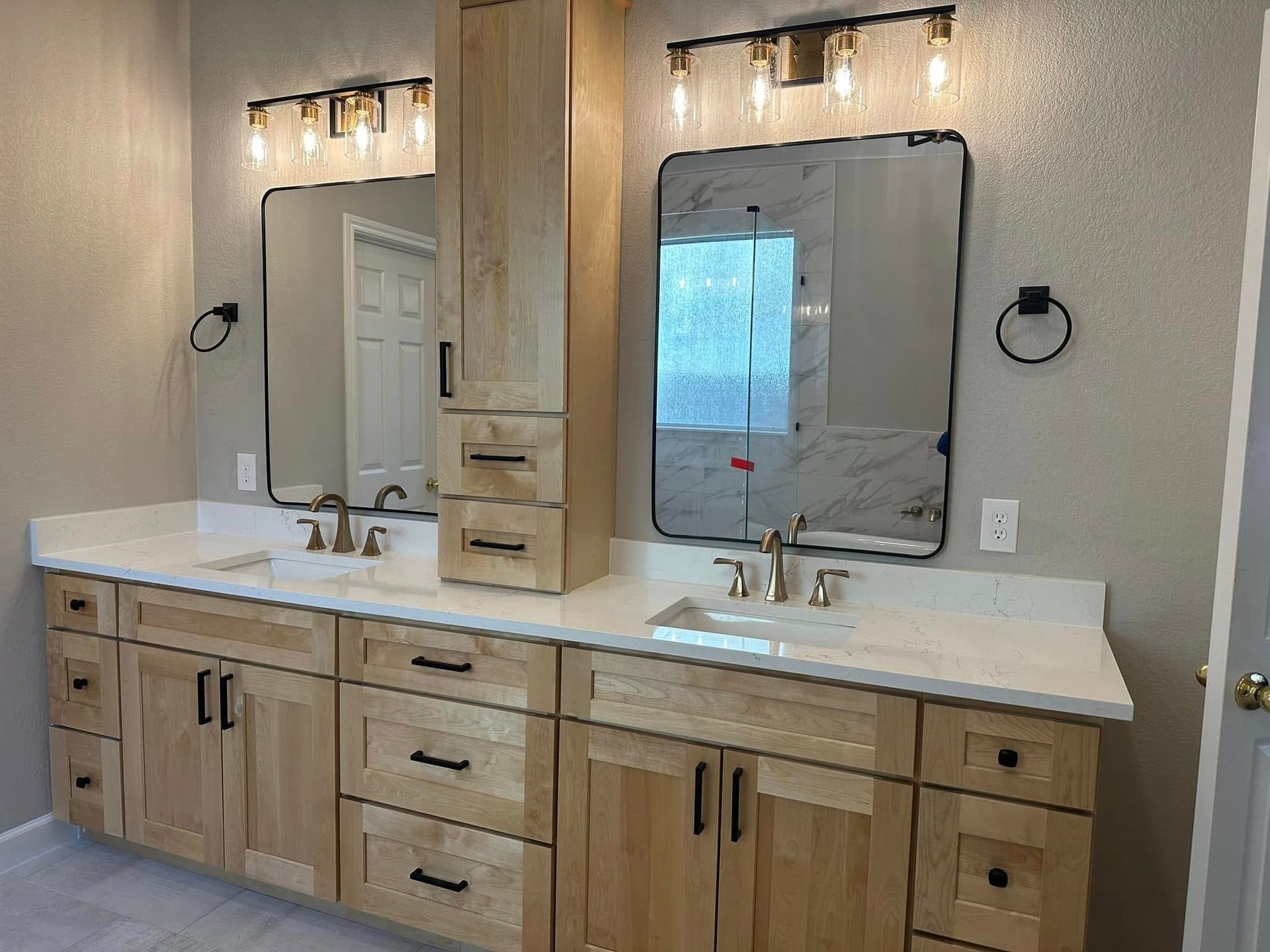 Modern bathroom vanity with two mirrors, lights, sinks, and wood cabinetry.