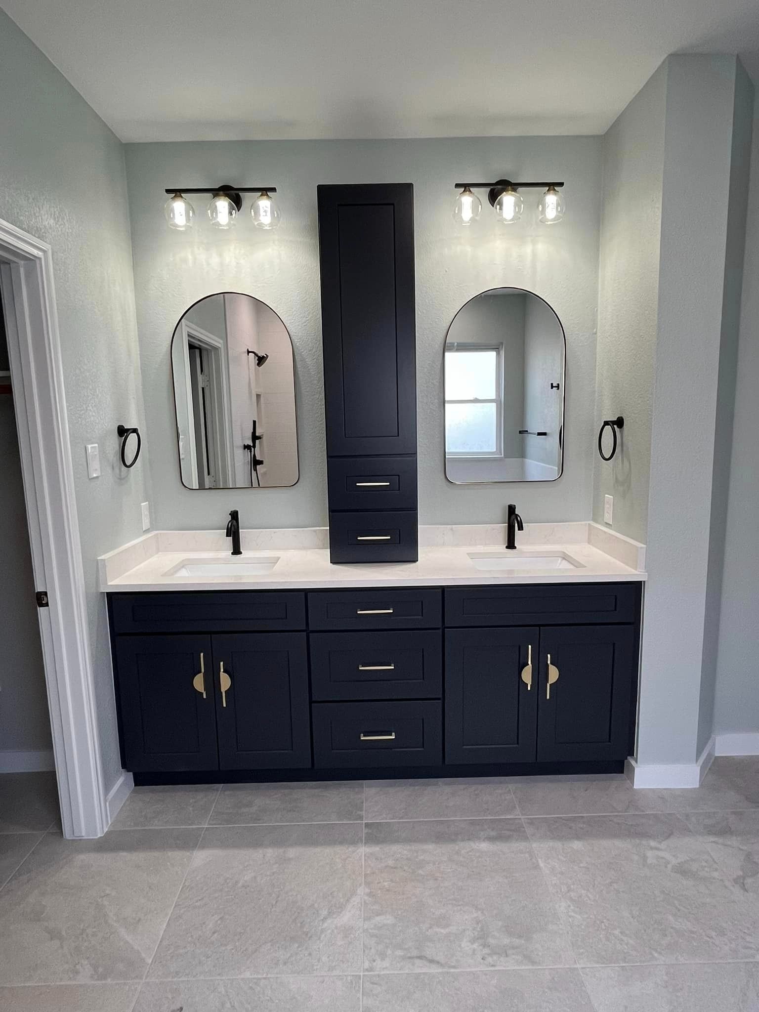 Modern bathroom vanity with double sinks, black cabinets, mirrors, and wall sconces