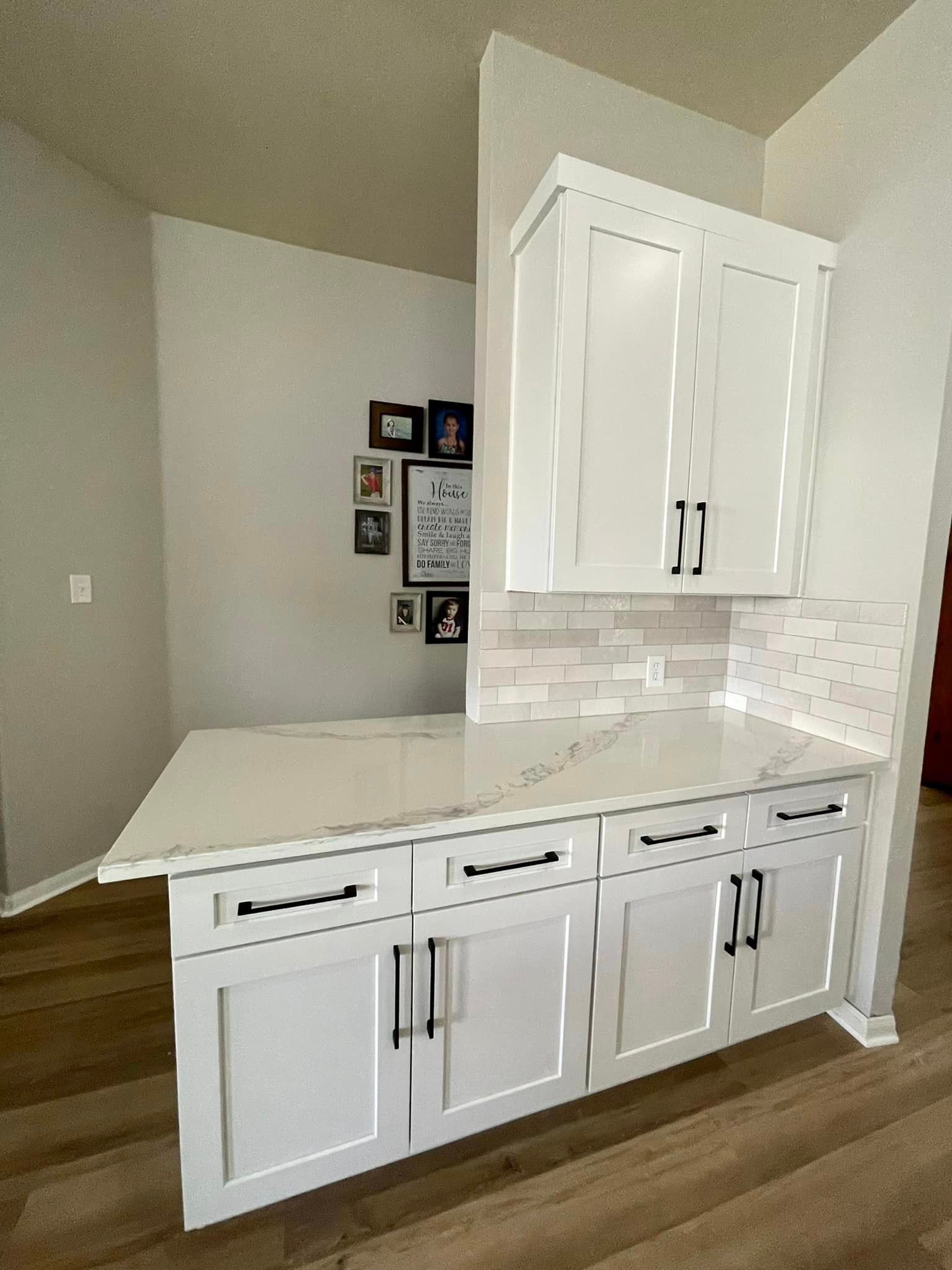 White kitchen cabinets with a gray tile backsplash and countertop in a corner alcove