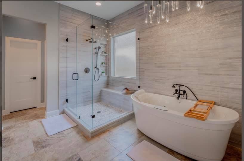 Modern bathroom with glass walk-in shower and freestanding bathtub on light tile floor