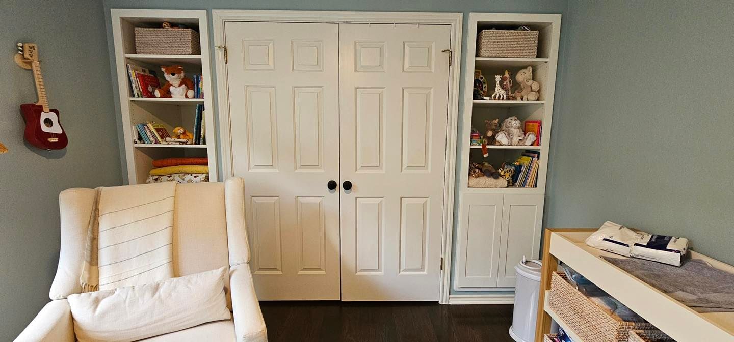 Small bedroom with white double closet doors, built-in shelves, a white chair, and a bed