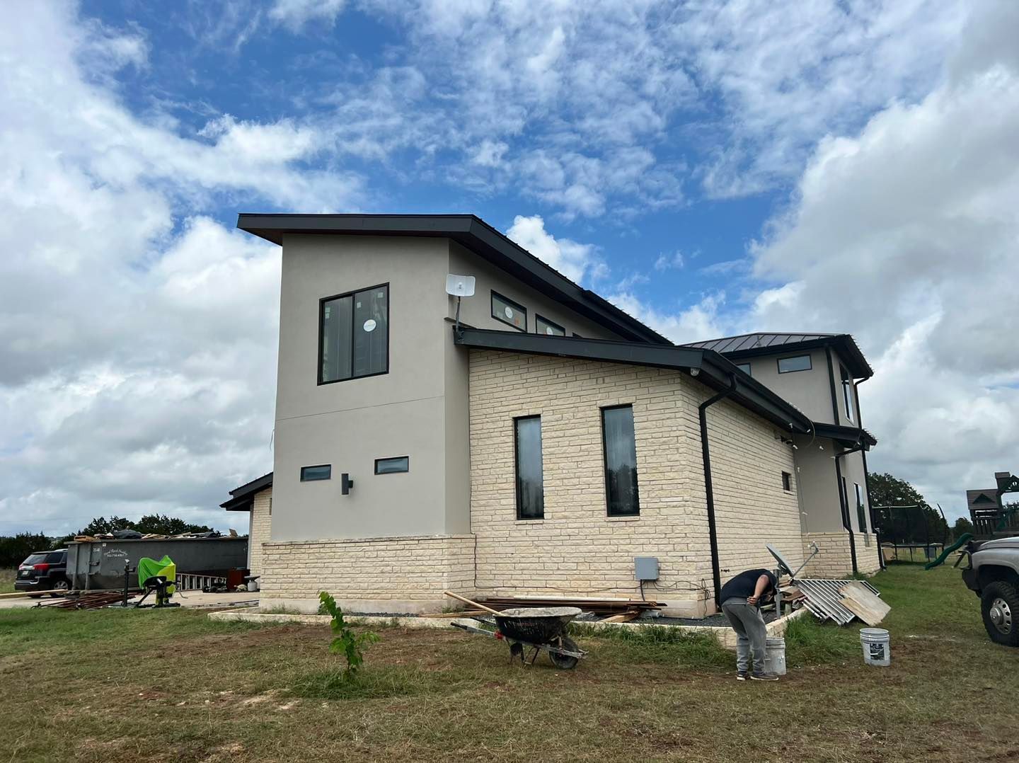 Partially built modern house with beige walls and a slanted roof under a cloudy sky