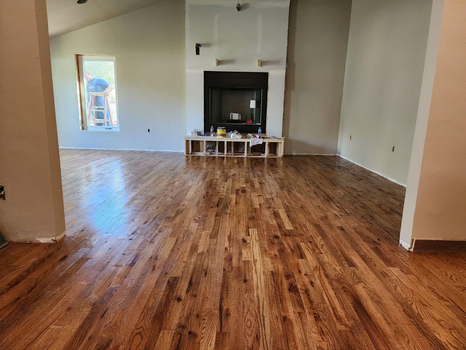 Empty living room with hardwood floors, a fireplace, and a wall mirror.