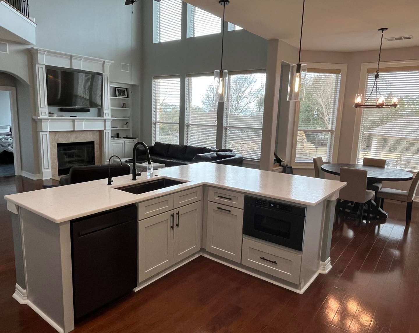 Modern open kitchen with white island, dark hardwood floors, and living area in background