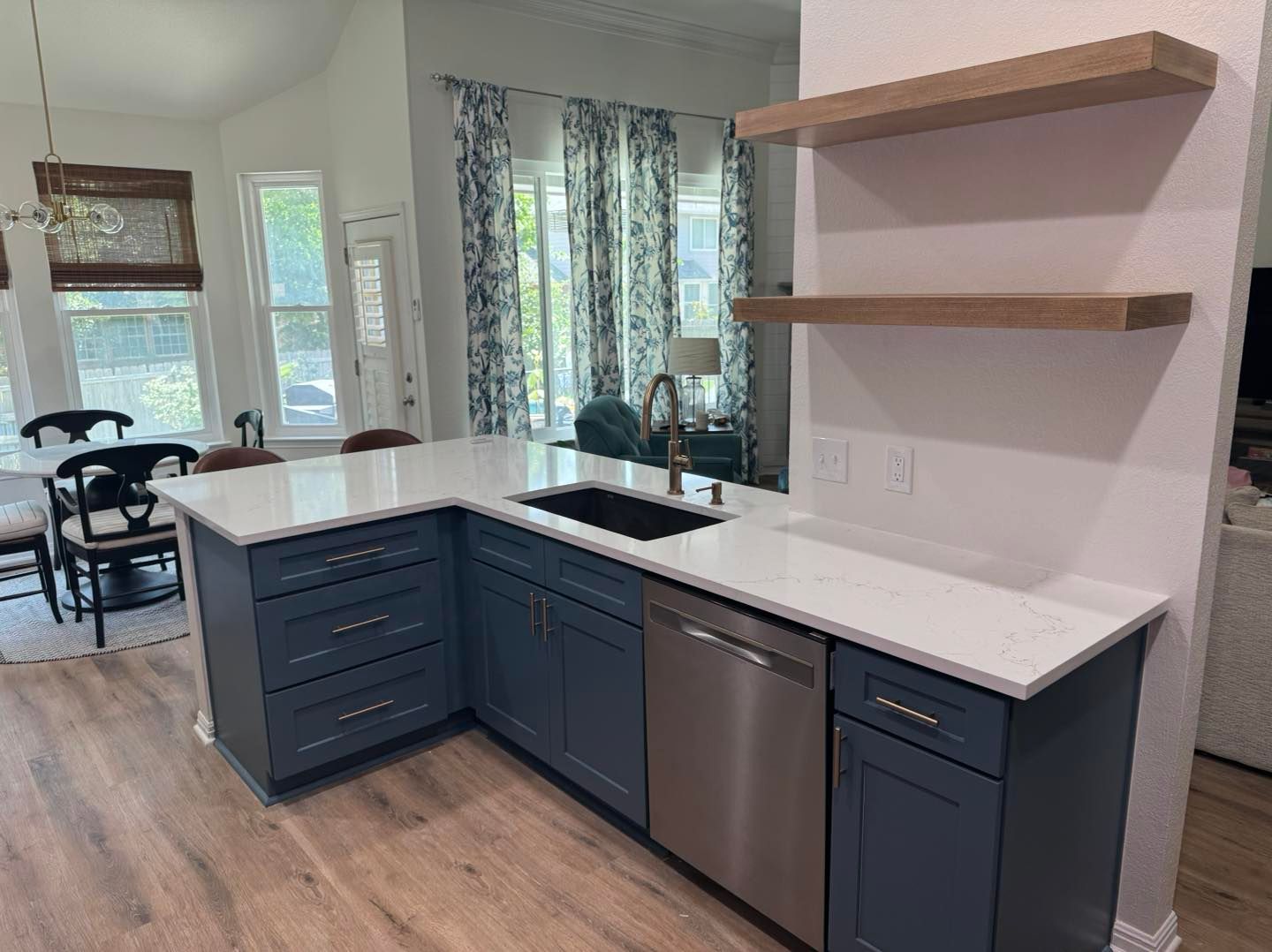 Modern kitchen with dark blue cabinets, white countertops, island sink, and open wood shelves