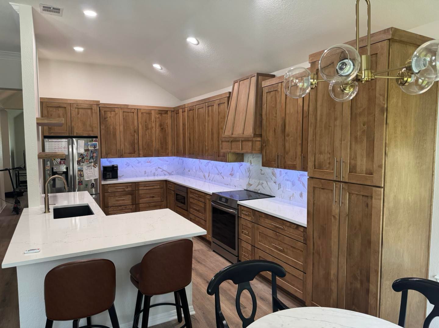 Modern kitchen with wood cabinets, white island, marble backsplash, and pendant lights